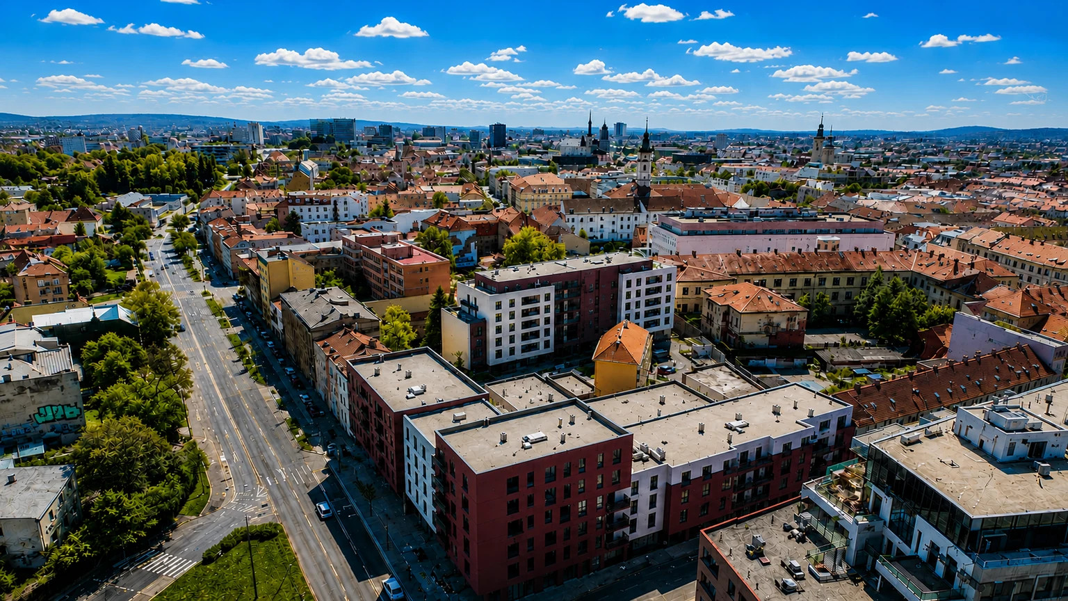 Сучасний житловий комплекс із підсвіченими вікнами, пішохідним переходом і рухом автомобілів на заході.